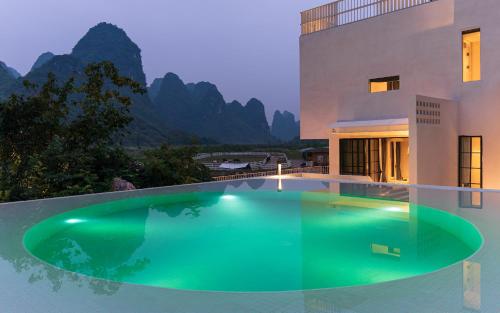 een zwembad voor een huis met bergen bij Yangshuo One Thousand and One Courtyard Views B&B in Yangshuo