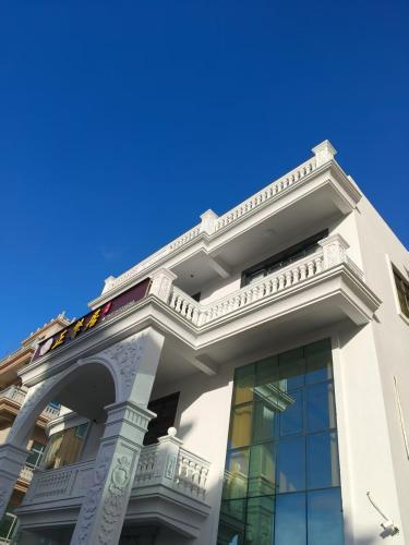 a white building with a balcony on top of it at Meizhou Island Zhengxinju Homestay in Xiashan