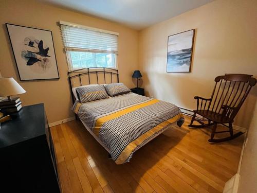 a bedroom with a bed and a chair and a window at Water front Golden Lake cottage - Calm and peaceful in Val-David