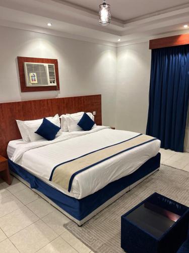 a large bed with blue pillows in a bedroom at أجنحة المدينة للشقق المفروشة in Al Madinah