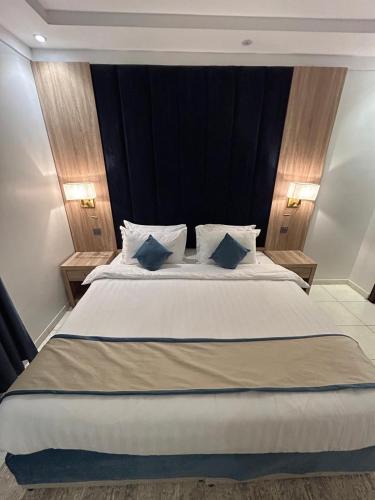 a bedroom with a large white bed with blue pillows at أجنحة المدينة للشقق المفروشة in Al Madinah