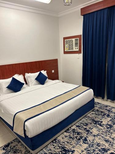 a bedroom with a large bed with blue curtains at أجنحة المدينة للشقق المفروشة in Al Madinah