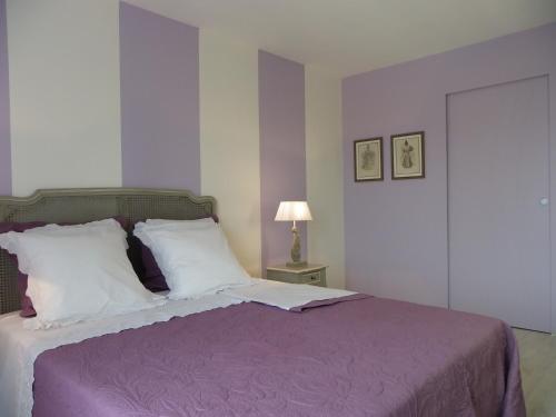 ein Schlafzimmer mit einem Bett mit einer lila Decke und einer Lampe in der Unterkunft Le Logis De Saint-Martin in Haute-Goulaine