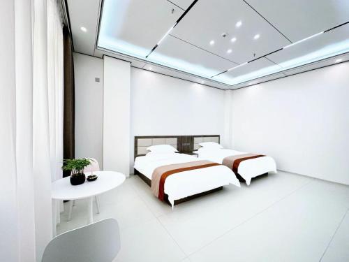 two beds in a white room with a table and a bedsenal at Meizhou Island Zhengxinju Homestay in Xiashan