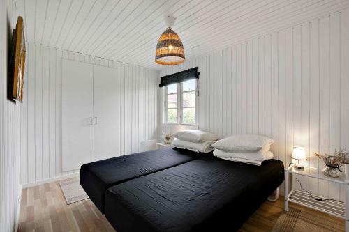 a bedroom with a black bed with two pillows on it at Lovely Cottage For Family And Friends in Kirke-Hyllinge