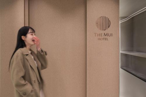 a woman is standing in front of a wall at The Mui Hotel in Seongnam