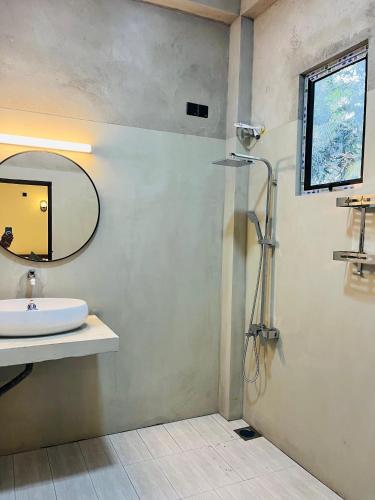 a bathroom with a sink and a mirror and a shower at Pixie Haven Lodge Hiriketiya in Dickwella