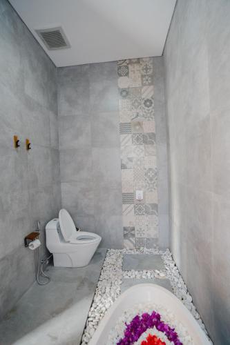 a bathroom with a toilet and a bath tub at Graha Madeline in Ketewel
