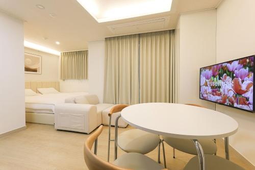 a room with a bed and a table and a tv at Marant Residence Hotel Busan Station in Busan