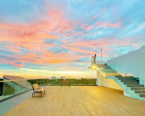a man standing on the edge of a balcony with a sunset at Queensland Suites at Aru Suites, Kota Kinabalu 2 Bedroom Family Suite in Kota Kinabalu