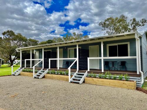 a blue house with white steps and a porch at Cootamundra Caravan Park in Cootamundra