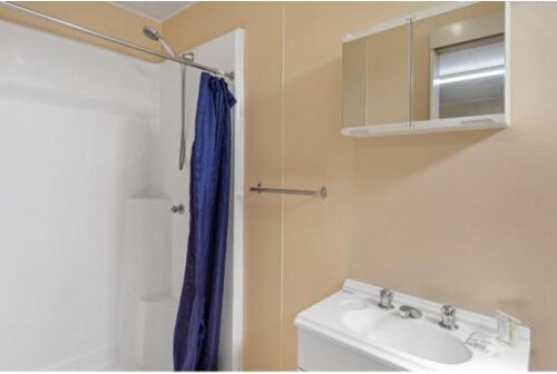 a bathroom with a sink and a blue shower curtain at Discovery Parks - Blackwater in Blackwater
