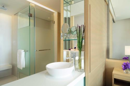 a bathroom with a sink and a glass shower at Avani Plus Riverside Bangkok Hotel in Bangkok