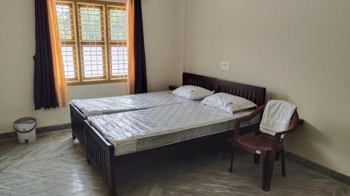 a bedroom with a bed with a chair and a window at Shri Ganesh Residency And Restaurant in Dharmastala