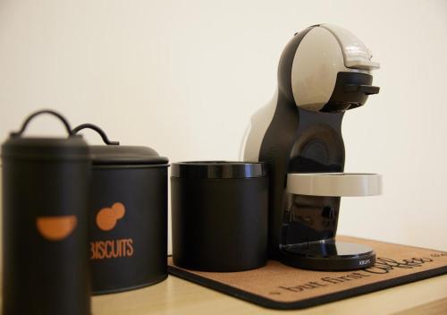 a coffee maker and two cups on a table at The Mazy-Self check in Malpensa Rho fiera in Busto Arsizio