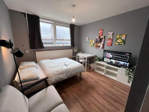 a bedroom with a bed and a tv and a couch at The Friary House - Central Guildford Personal 1 Bedroom Budget Apartment in Guildford
