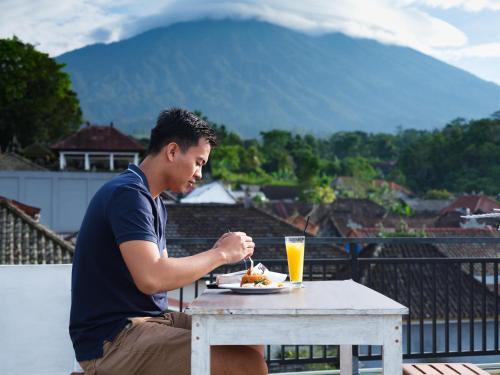 a man sitting at a table with a plate of food at Sakaloka Mountain Homestay in Besakih