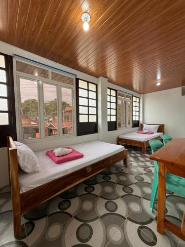 a room with two beds and a table and windows at Agoo Tourist Cabin in Agoo