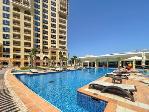 a large swimming pool with chairs and buildings at StayShort - Stylish Relaxing 3-Bedroom Apartment Perfect for Family in Palm Jumeirah in Dubai