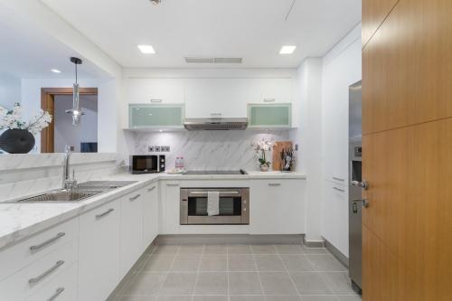 a white kitchen with green cabinets and a sink at StayShort - Stylish Relaxing 3-Bedroom Apartment Perfect for Family in Palm Jumeirah in Dubai