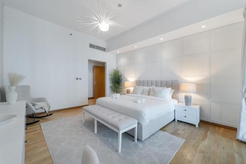 a white bedroom with a white bed and a bench at StayShort - Stylish Relaxing 3-Bedroom Apartment Perfect for Family in Palm Jumeirah in Dubai