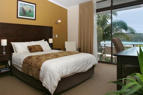 a bedroom with a large bed and a balcony at The Whale Inn in Narooma