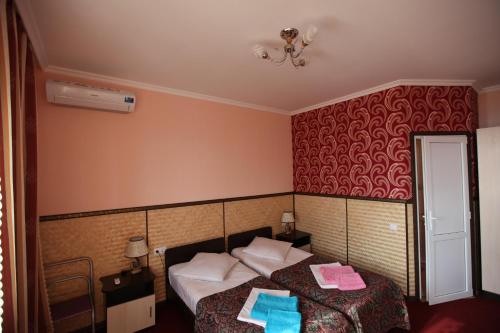 a bedroom with two beds and a red wall at Гостевой дом Барс Абхазия in Tsandrypsh