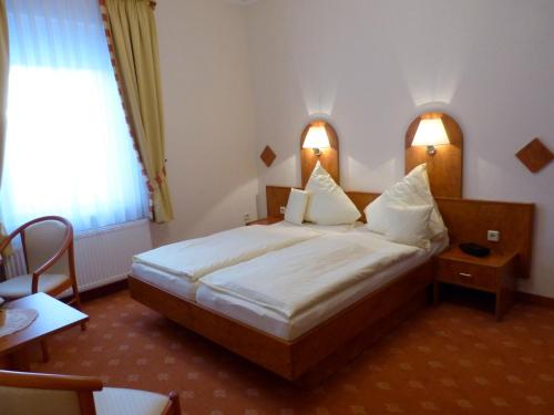 a bedroom with a large bed with two lights on it at Ferienhotel Wolfsmühle in Rodishain