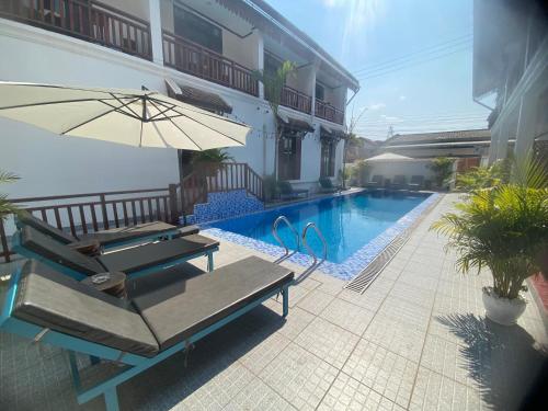a patio with a table and an umbrella next to a pool at Luangprabang Town Pavilion Hotel in Luang Prabang