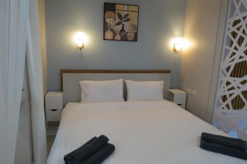 a bedroom with a white bed with two black objects on it at Baan Bee Residence in Nong Prue