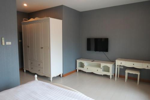 a bedroom with a white cabinet and a tv at Baan Bee Residence in Nong Prue