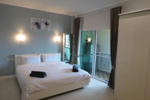 a bedroom with a white bed with two black bags on it at Baan Bee Residence in Nong Prue