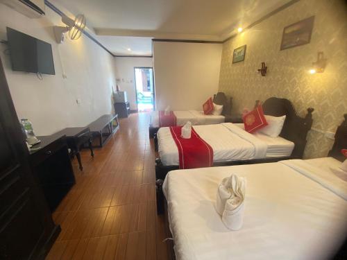 a hotel room with three beds and a table and chairs at Luangprabang Town Pavilion Hotel in Luang Prabang