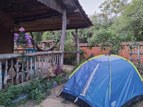 a blue tent in a garden next to a fence at Camping Serra São José in Tiradentes