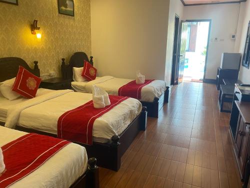 a hotel room with three beds with red and white sheets at Luangprabang Town Pavilion Hotel in Luang Prabang