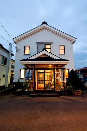 a large white house with a front porch at Pension Jokura in Hakodate