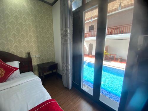 a bedroom with a swimming pool seen through a glass door at Luangprabang Town Pavilion Hotel in Luang Prabang