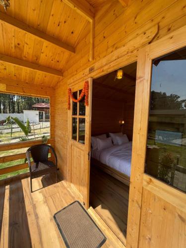 a bedroom in a wooden cabin with a bed and a window at Mountail Eco Resort in Netarhāt