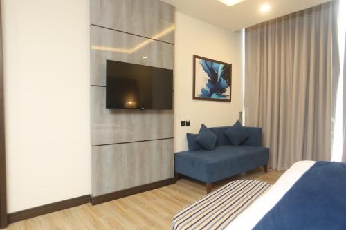 a bedroom with a blue chair and a television at Best Western Hotel Rawalpindi Central in Rawalpindi