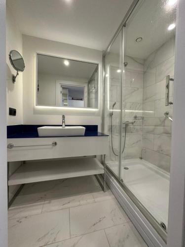 a white bathroom with a sink and a shower at Orbi City - "A" in Batumi
