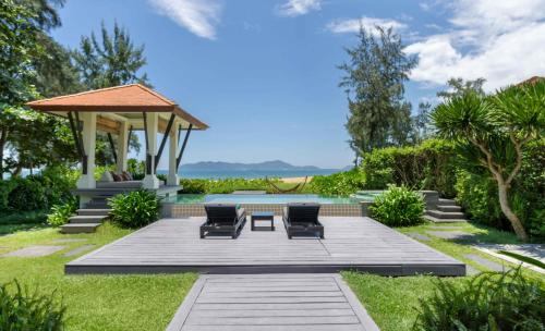a garden with two chairs and a gazebo at Banyan Tree Lang Co in Lang Co