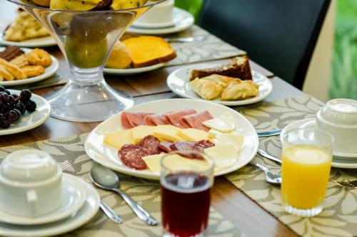 a table with plates of food and glasses of orange juice at Sky Premium Hotel Gramado - Ótima Localização in Gramado
