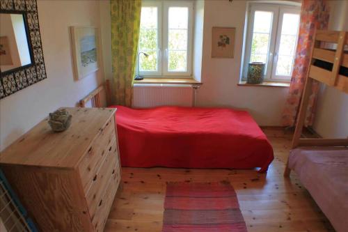 a bedroom with a red bed and two windows at Cozy Country House On Ærø in Soby Mark