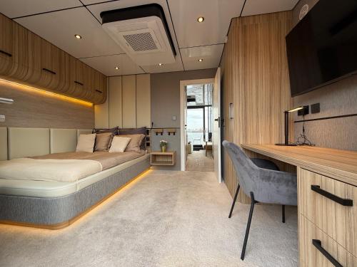 Un dormitorio con una cama y un escritorio con televisión. en Villa Perla Mare - Sauna Experience - On a lake near Amsterdam, en Vinkeveen