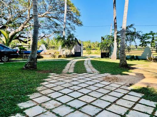 a stone walkway in a park with palm trees at Tranquil Sanctuary Yala in Tissamaharama