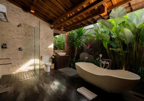 a bathroom with a tub and some plants at Natajiwa Village in Seminyak