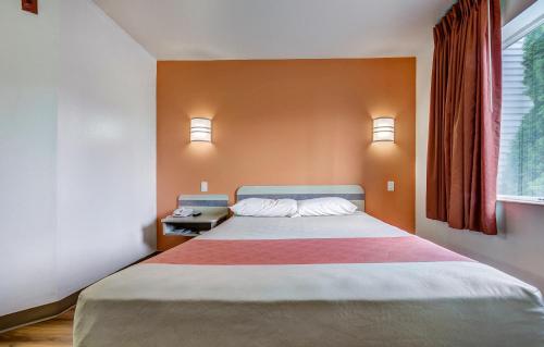 a bedroom with a large bed with orange walls and a window at Motel 6-Roseburg, OR in Roseburg