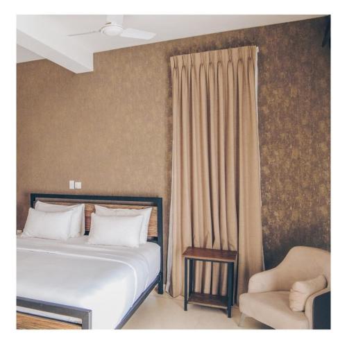 a bedroom with a bed and a chair at The Manor Hanthana in Kandy
