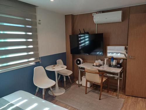 a room with a table and chairs and a television at Louis Hotel in Gangneung