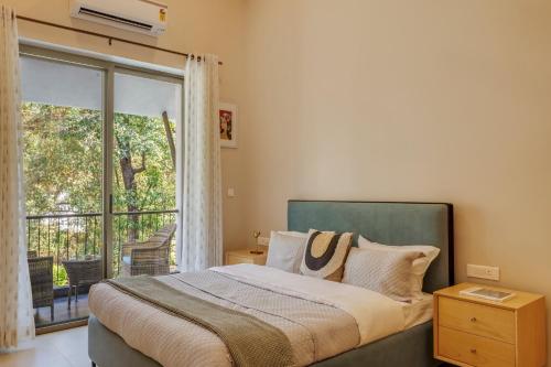 una camera da letto con un letto e una grande finestra di Trezora Candolim - Luxury 4bhk villa with pool a Goa